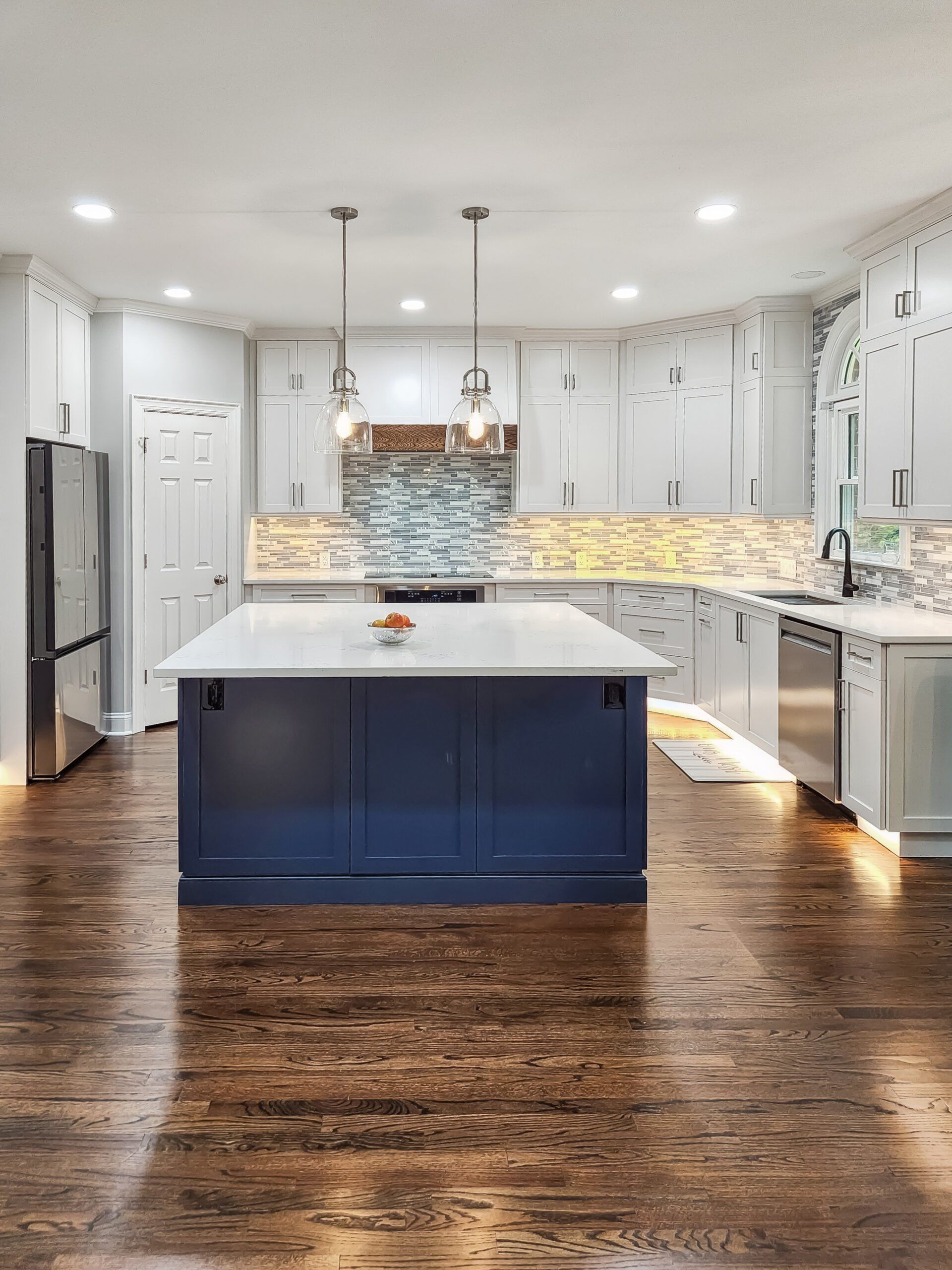A kitchen with white cabinets and stainless steel appliances and a blue island.