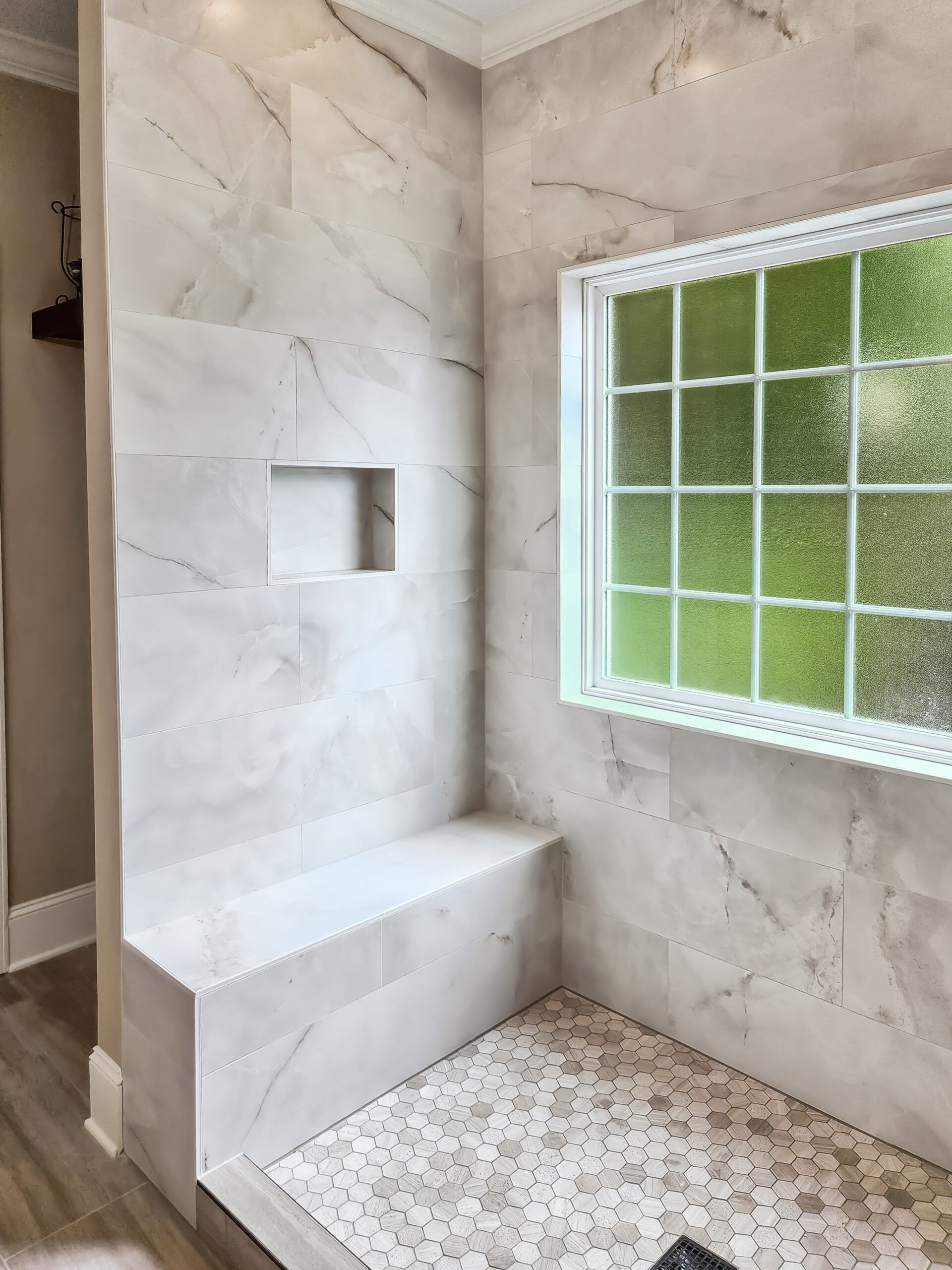 A bathroom with a walk in shower and a window.
