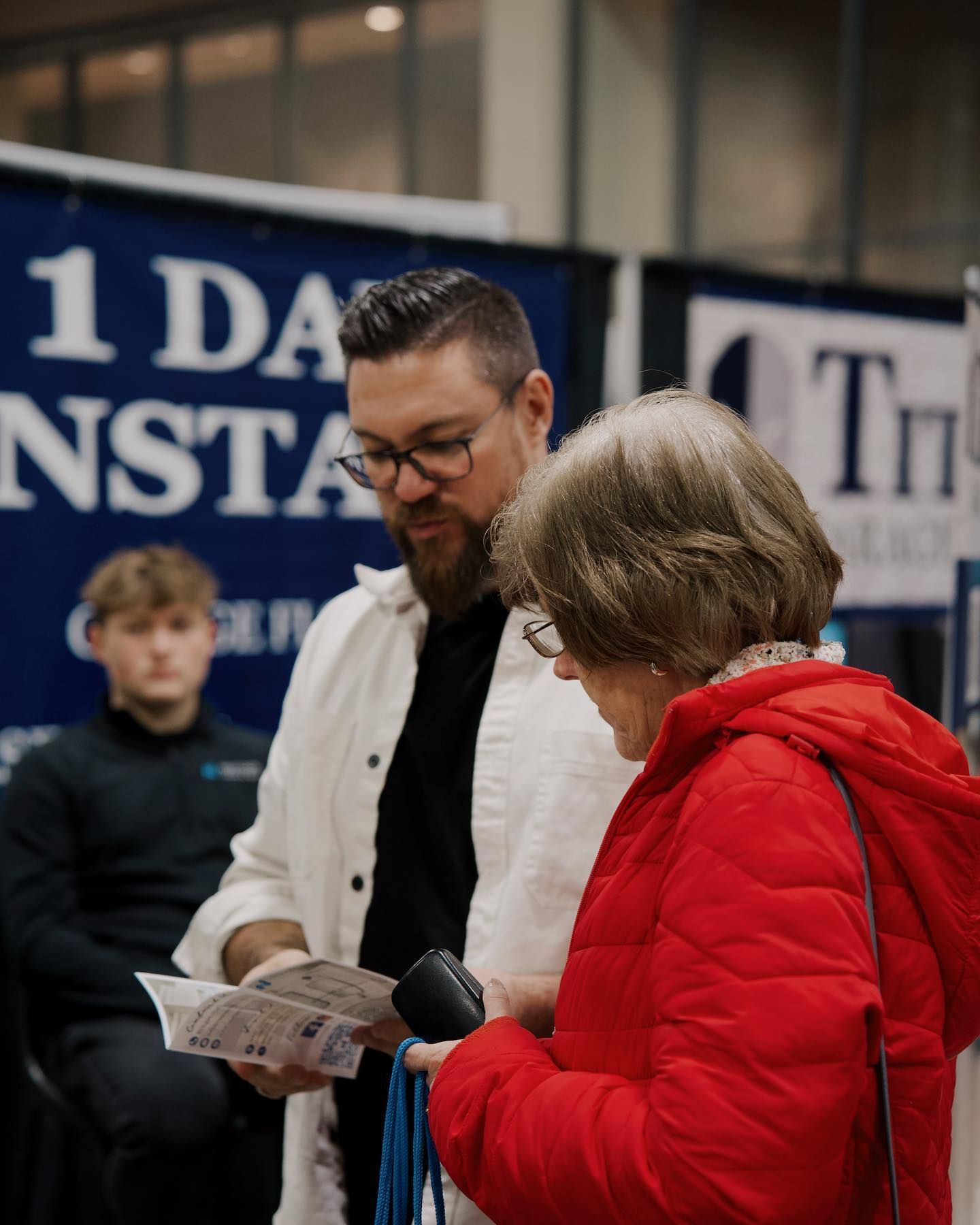 A man is talking to a woman in a red jacket.
