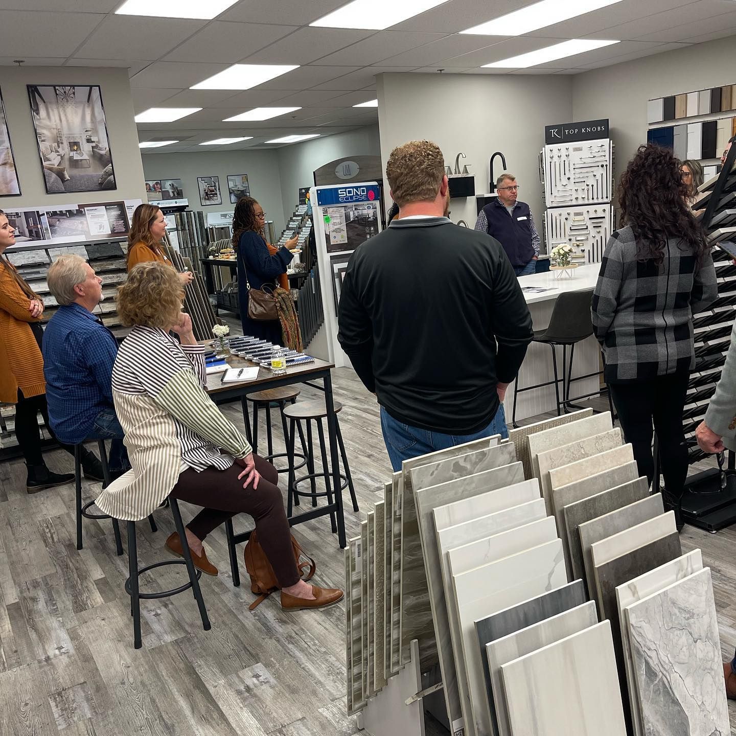 A group of people are standing around a table in a tile store.
