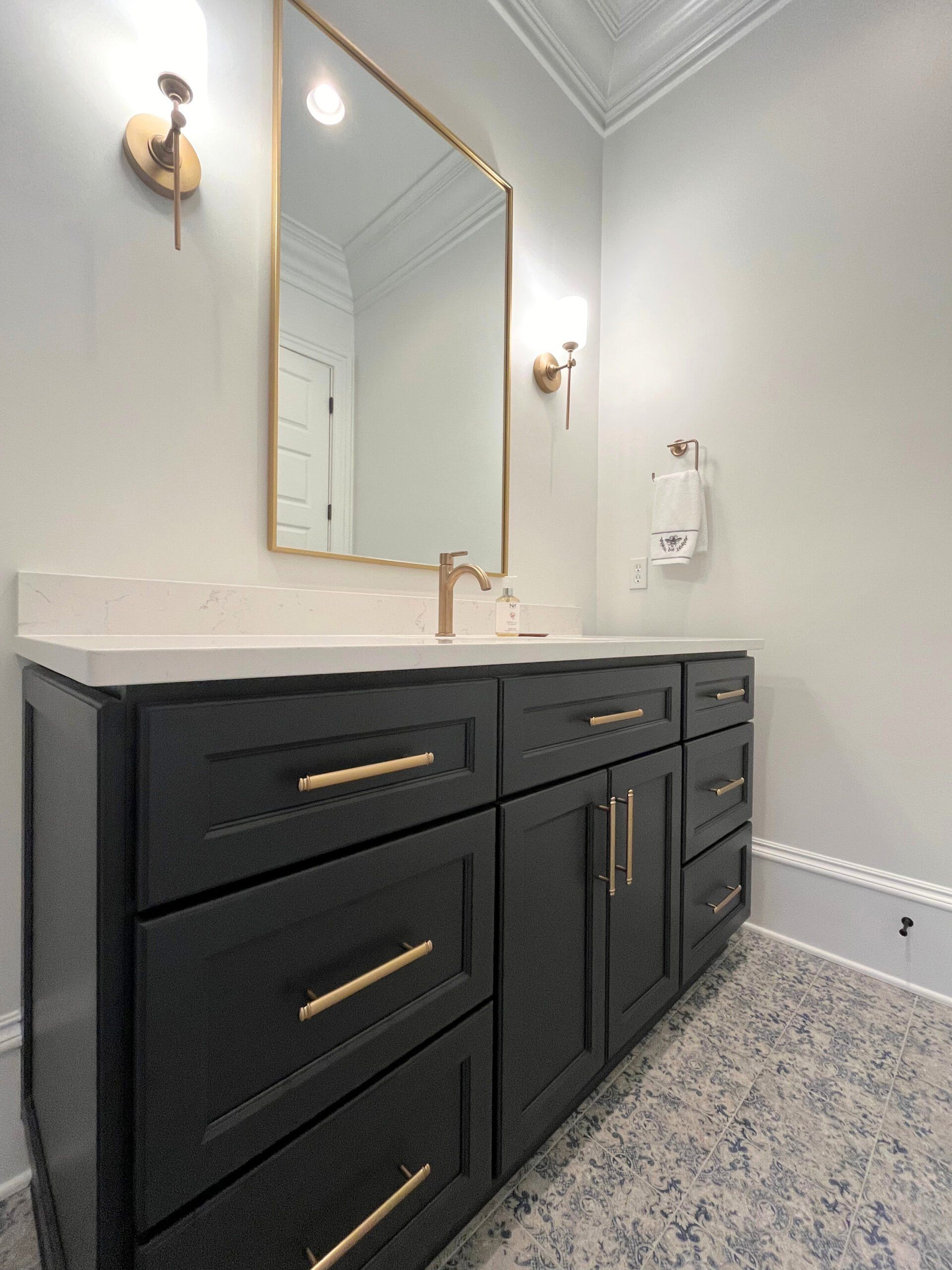A bathroom with black cabinets and a large mirror