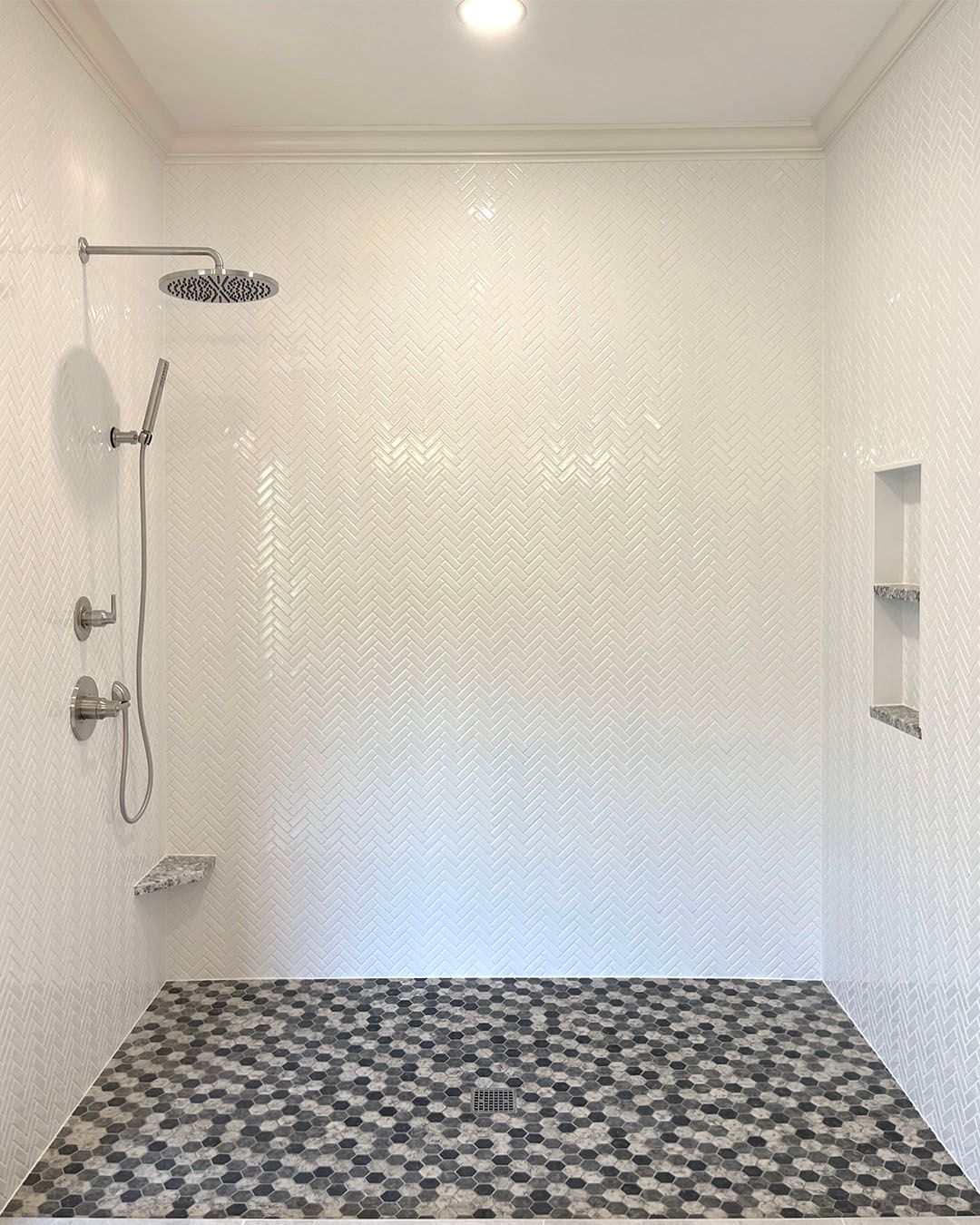 A shower with a shower head and a black and white tile floor.