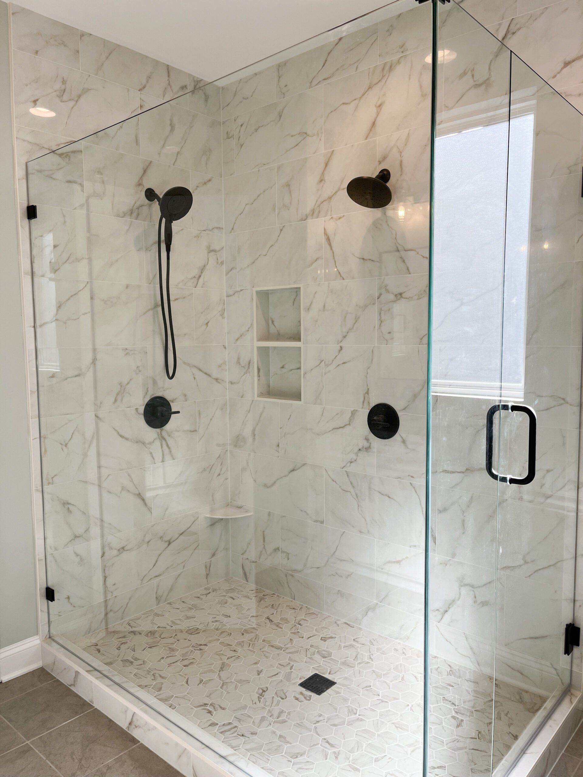A bathroom with a walk in shower with a glass door