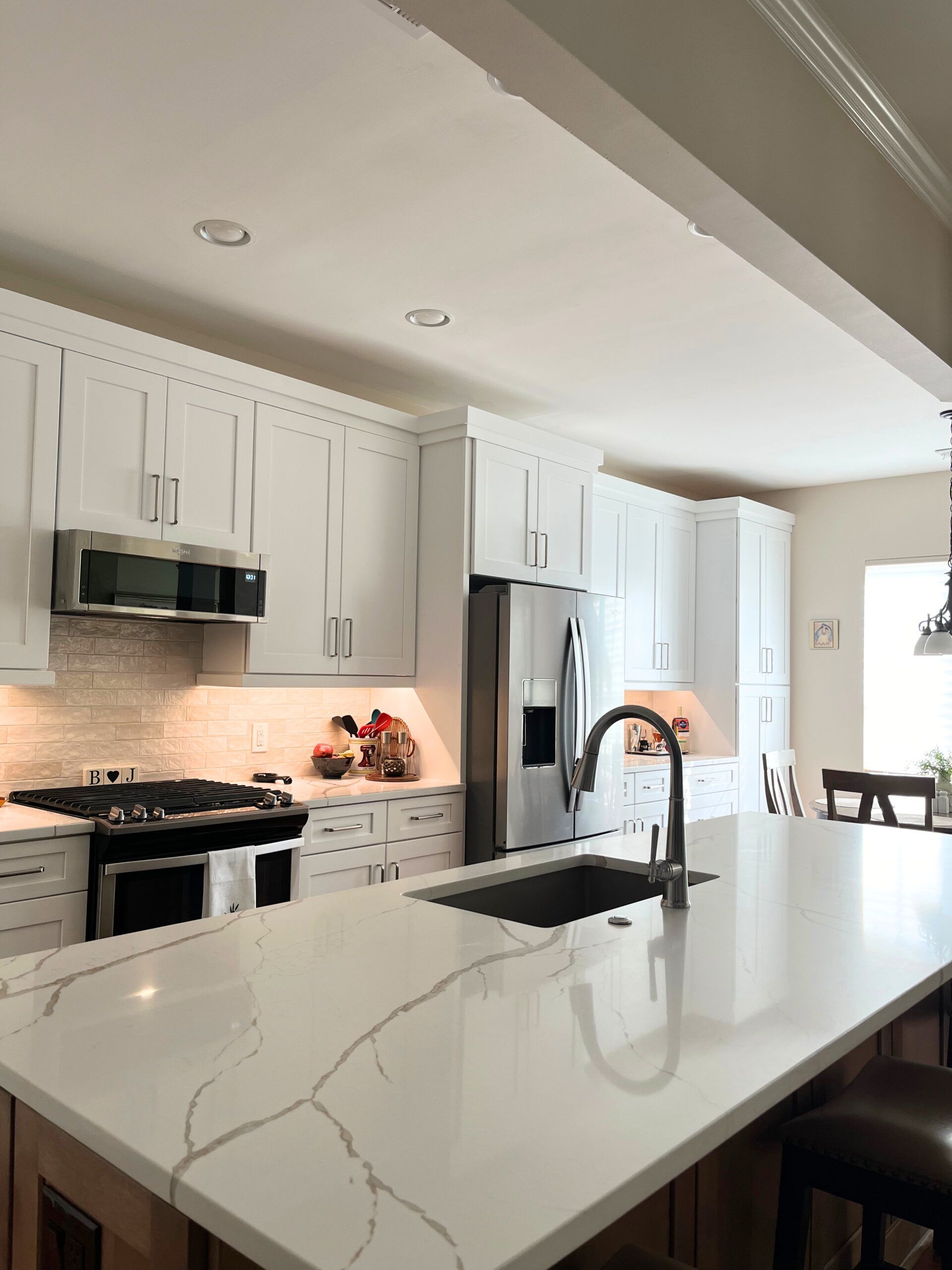 A kitchen with white cabinets , a sink , a refrigerator , and a stove.