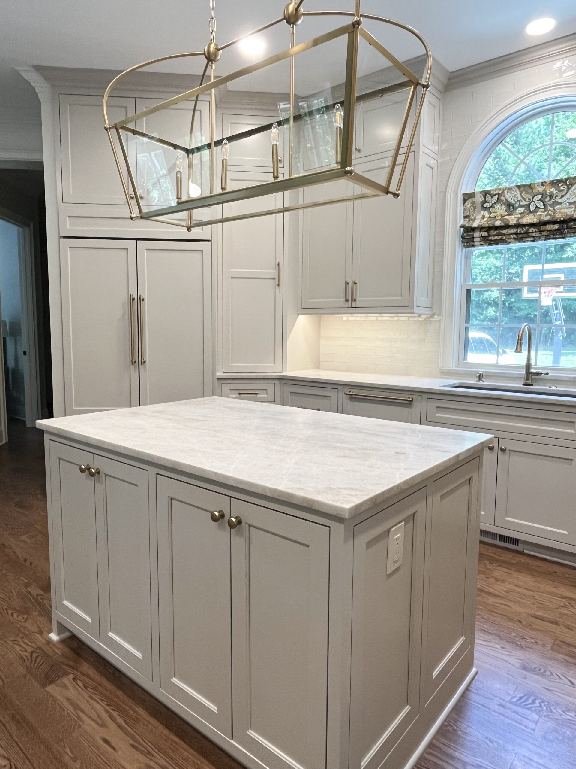 A kitchen with white cabinets and a large island with a marble counter top.