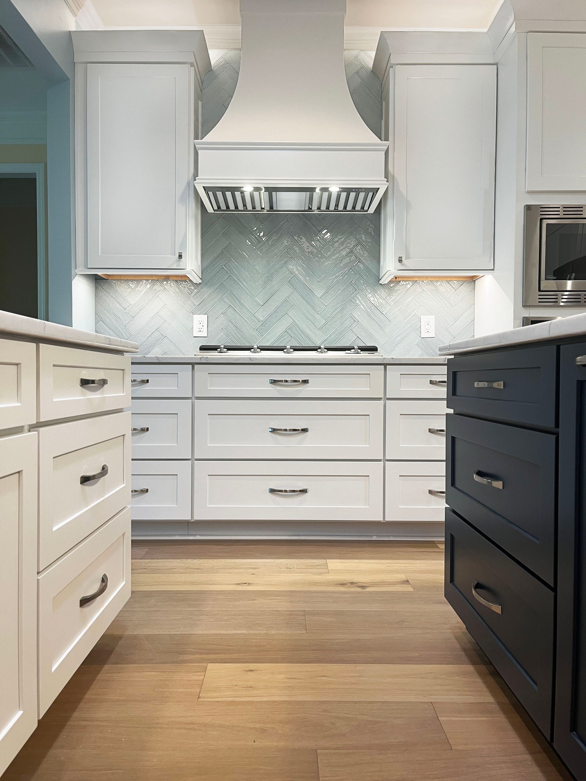 A kitchen with white cabinets and blue drawers and a stove top oven