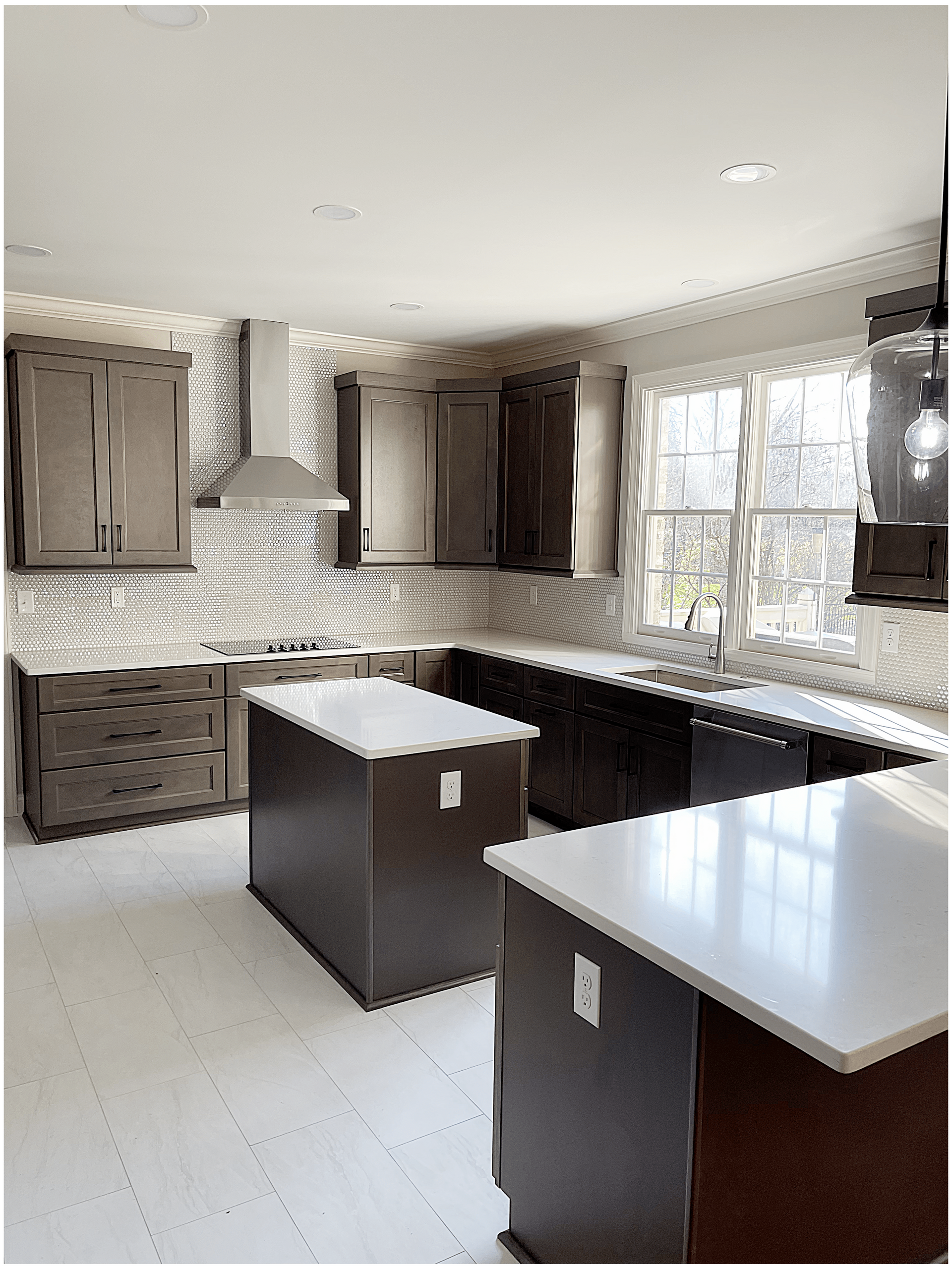 A kitchen with two islands and a stove top oven.