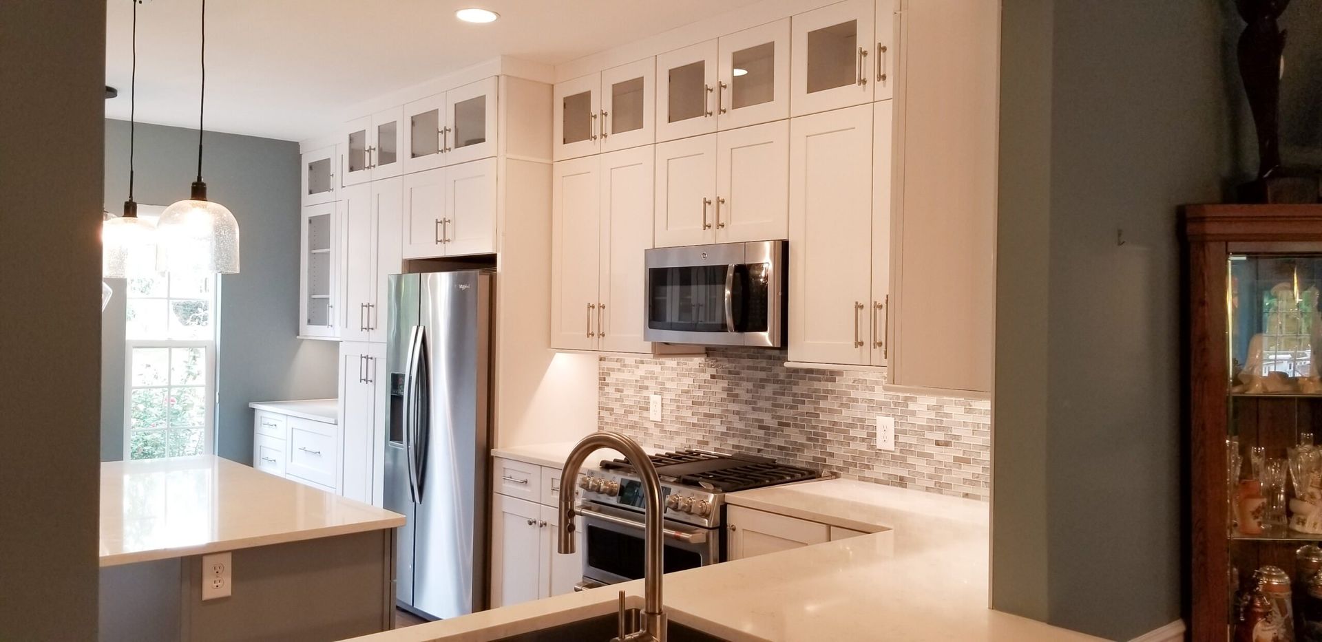 A kitchen with white cabinets , stainless steel appliances , a sink and a refrigerator.