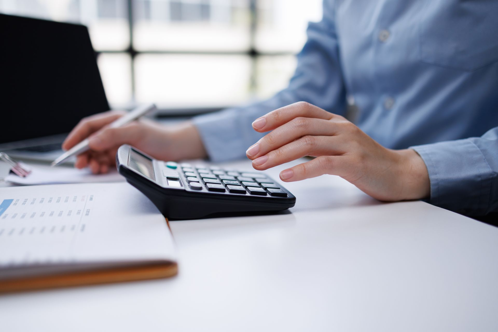 Person using a calculator while reviewing financial documents at a desk.