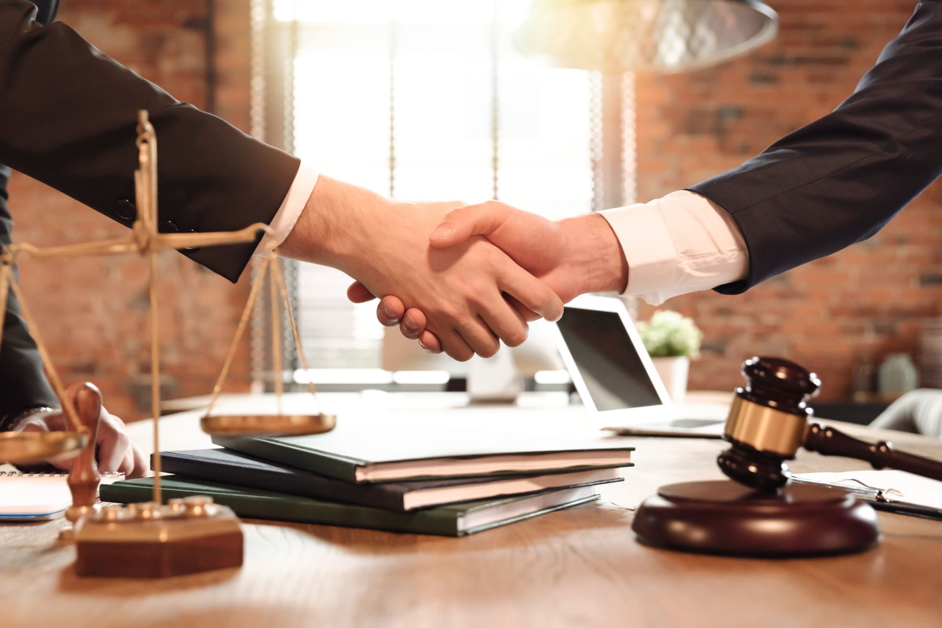 Handshake between two businesspeople at a desk with law books and a gavel