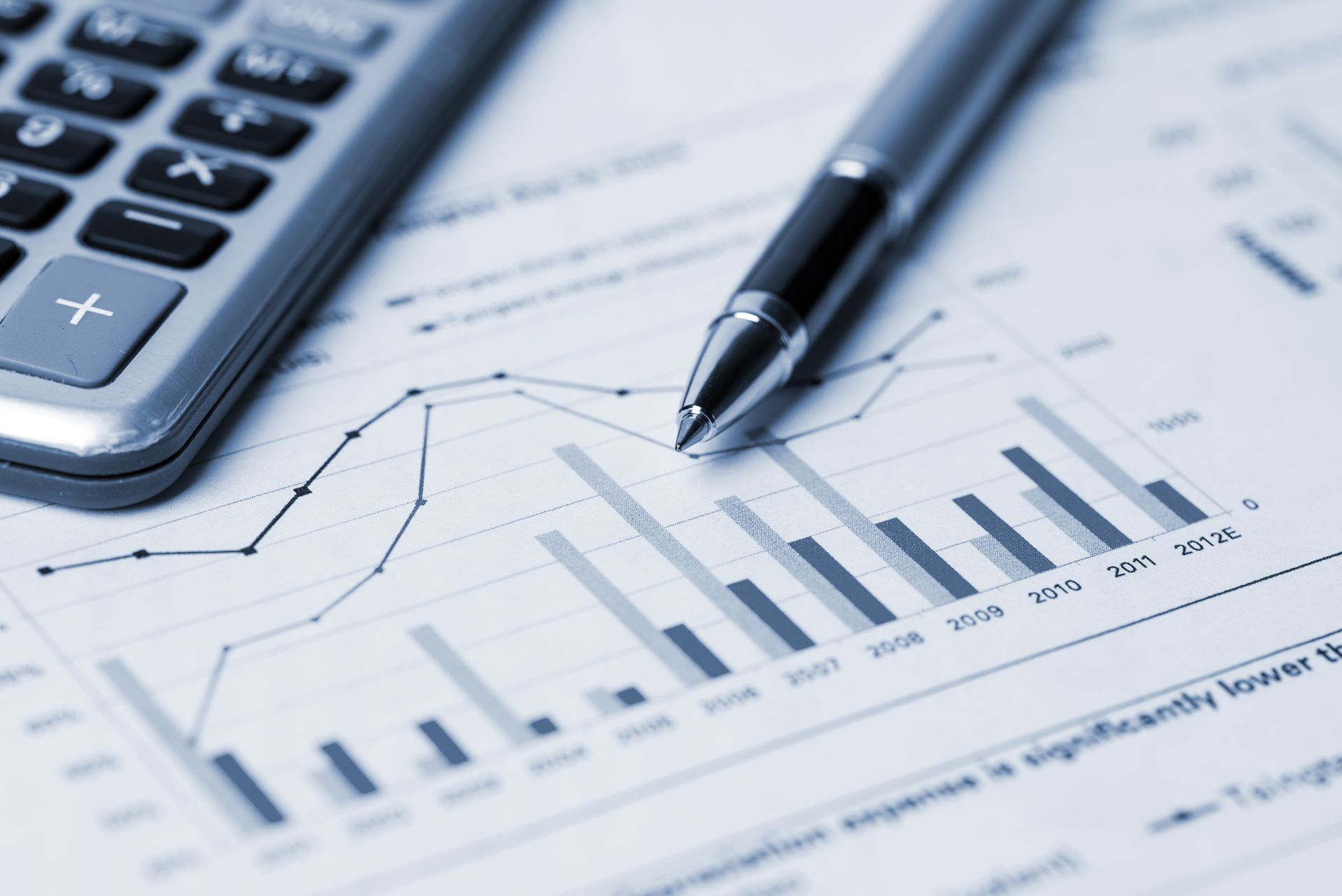Calculator and pen on a business graph with bar and line charts, showing financial data. Calculator and pen on a business graph with bar and line charts, showing financial data.