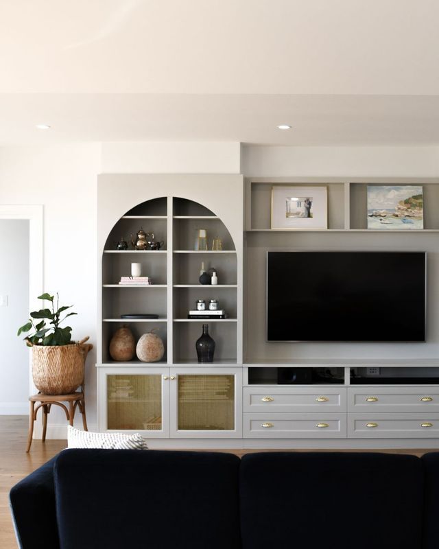 Modern living room with built-in shelving, TV, and a dark sofa in the foreground