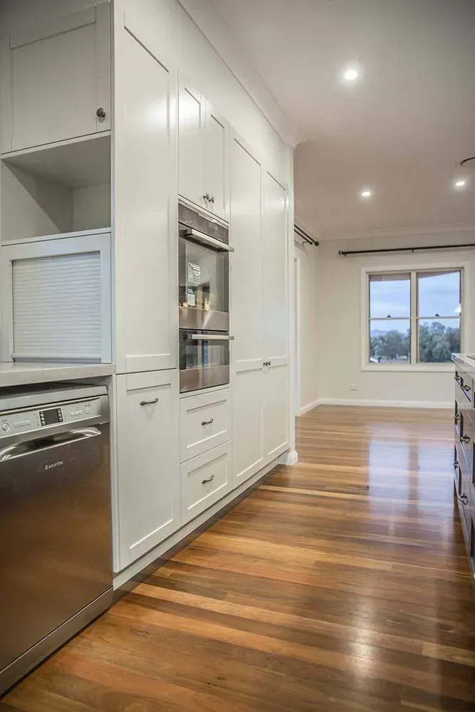 Bright Kitchen Hallway with White Cabinets, Wood Floors, Built-In Appliances — Simmonds Kitchens in Tamworth, NSW