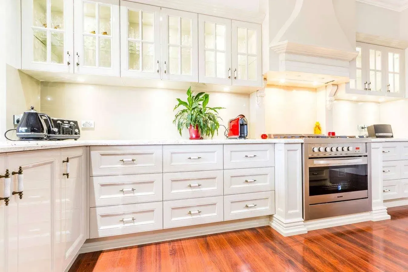 Bright White Kitchen with Cabinets, Countertop Appliances, Red Accents, and Wooden Floor — Simmonds Kitchens in Narrabri, NSW