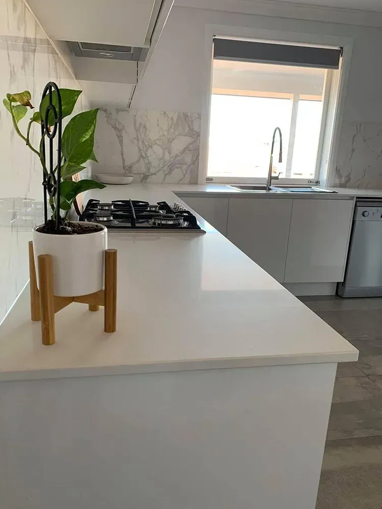 Modern White Kitchen with Island, Gas Stove, Sink, and A Potted Plant in A Wooden Stand — Simmonds Kitchens in Quirindi, NSW