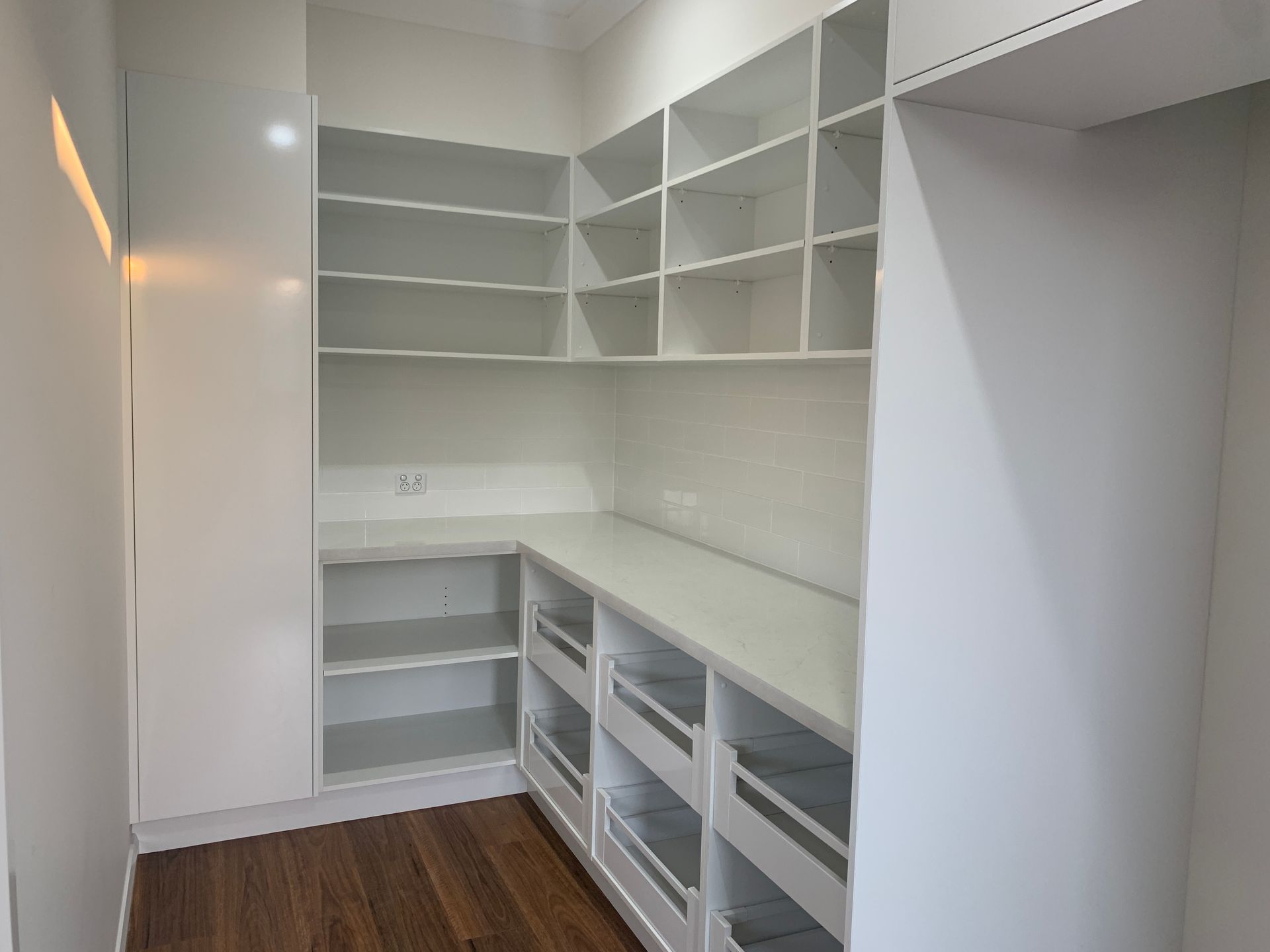 White Built-In Walk-In Closet with Shelves, Drawers, and Hanging Space on Wood Flooring — Simmonds Kitchens in Tamworth, NSW