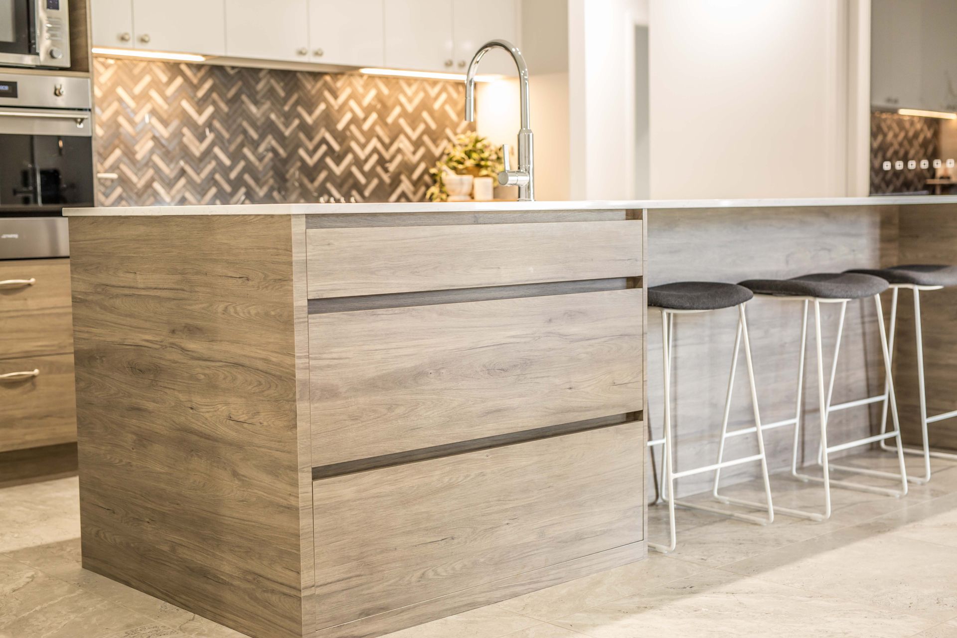 Modern Kitchen with Wood Island, White Cabinetry, Herringbone Backsplash, and Bar Stools — Simmonds Kitchens in Tamworth, NSW