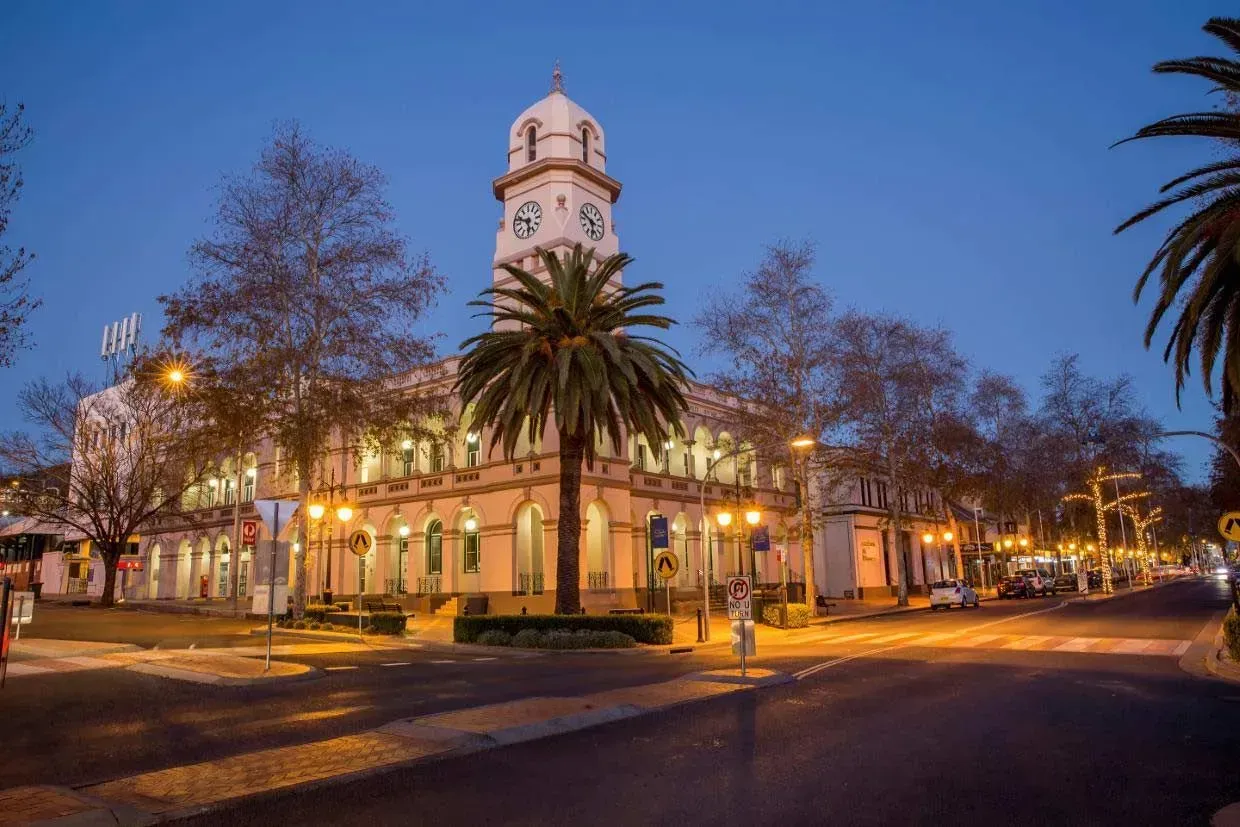 A Large Building With a Clock Tower and Palm Trees in Front of It — Simmonds Kitchens & Detailed Joinery in Tamworth, NSW