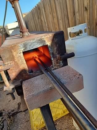 A piece of metal is being heated in a furnace next to a propane tank.