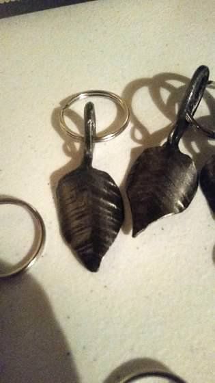 A pair of leaf shaped keychains sitting on top of a table.