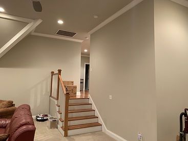 Staircase with wooden steps and railing, leading up to a hallway. Light-colored walls and carpet.