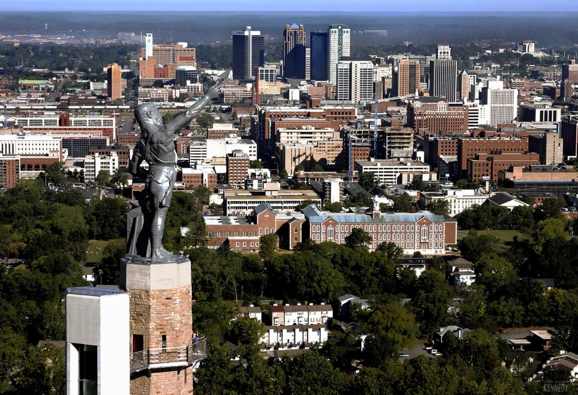 The Vulcan statue overlooks the cityscape of Birmingham, Alabama, with skyscrapers visible in the background.