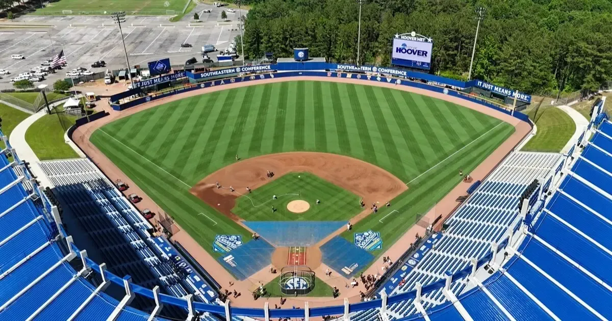 An aerial view of a baseball stadium with blue seating, a manicured green field, and a dirt infield.