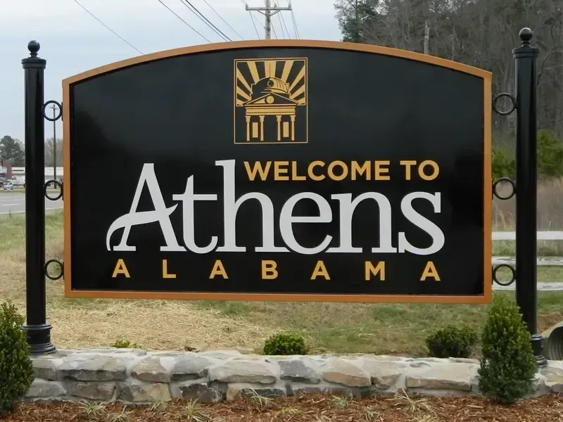 Welcome to Athens, Alabama sign in black, gold, and white with stone base