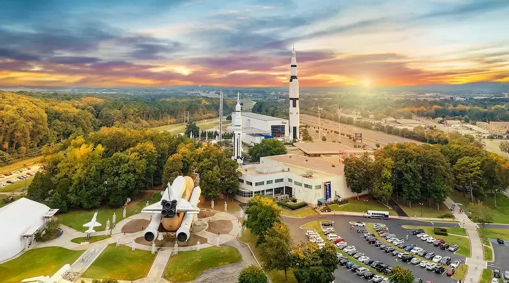 Aerial view of the U.S. Space & Rocket Center in Alabama at sunset, featuring a space shuttle and rockets on the campus.