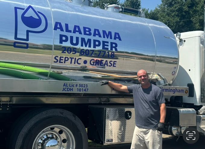 A man is standing in front of an alabama pumper septic grease truck.