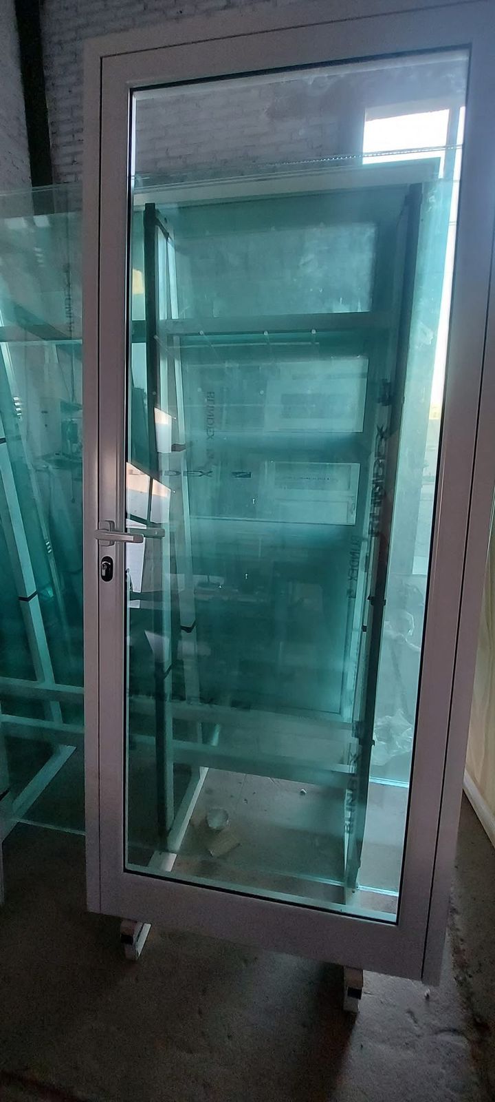 White glass-front appliance with interior shelves, standing on small legs indoors.