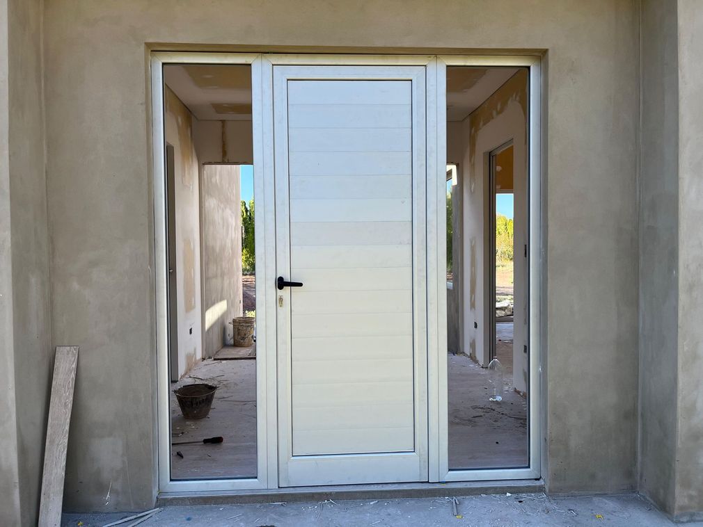 White front door with sidelights in a stucco house entrance under construction