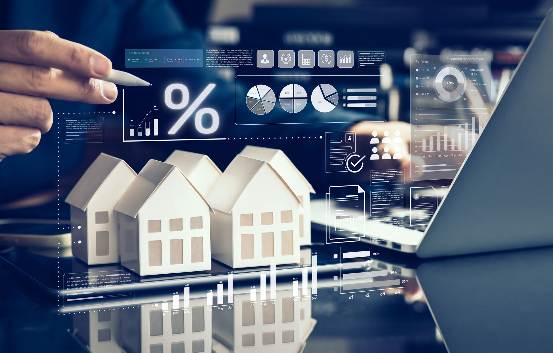 Person points at the interest rate symbol above paper houses and a laptop with financial data.