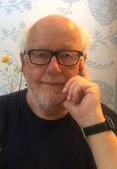 ein Mann mit Bart und Brille hält seine Hand an den Mund
