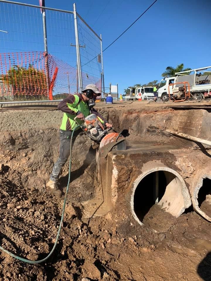 Construction Worker Cutting Concrete Pipes With a Power Saw — Dondarra Concrete Cutting & Drilling in Parkhurst, QLD
