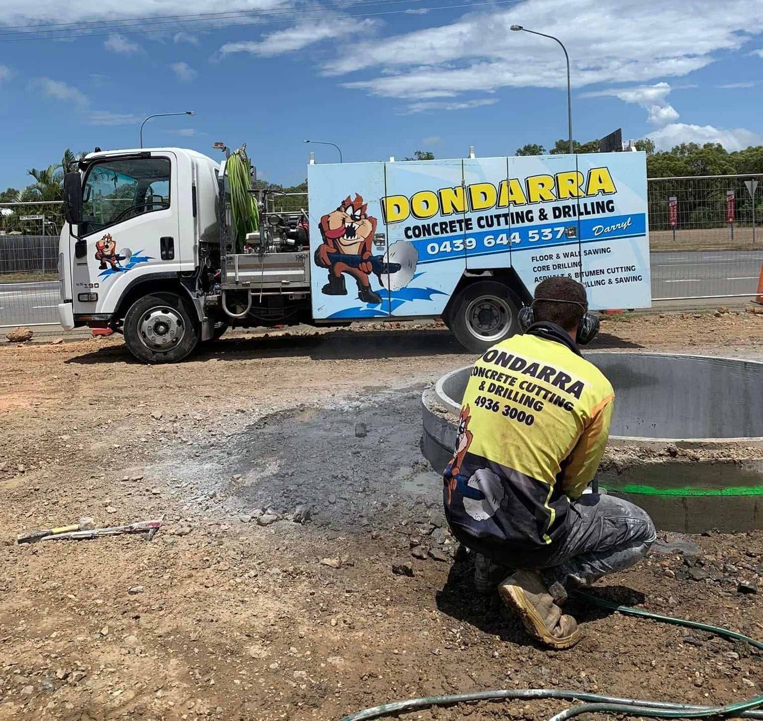 Construction site with concrete wall, dirt, rocks, and palm trees under a blue sky. — Dondarra Concrete Cutting & Drilling in Parkhurst, QLD