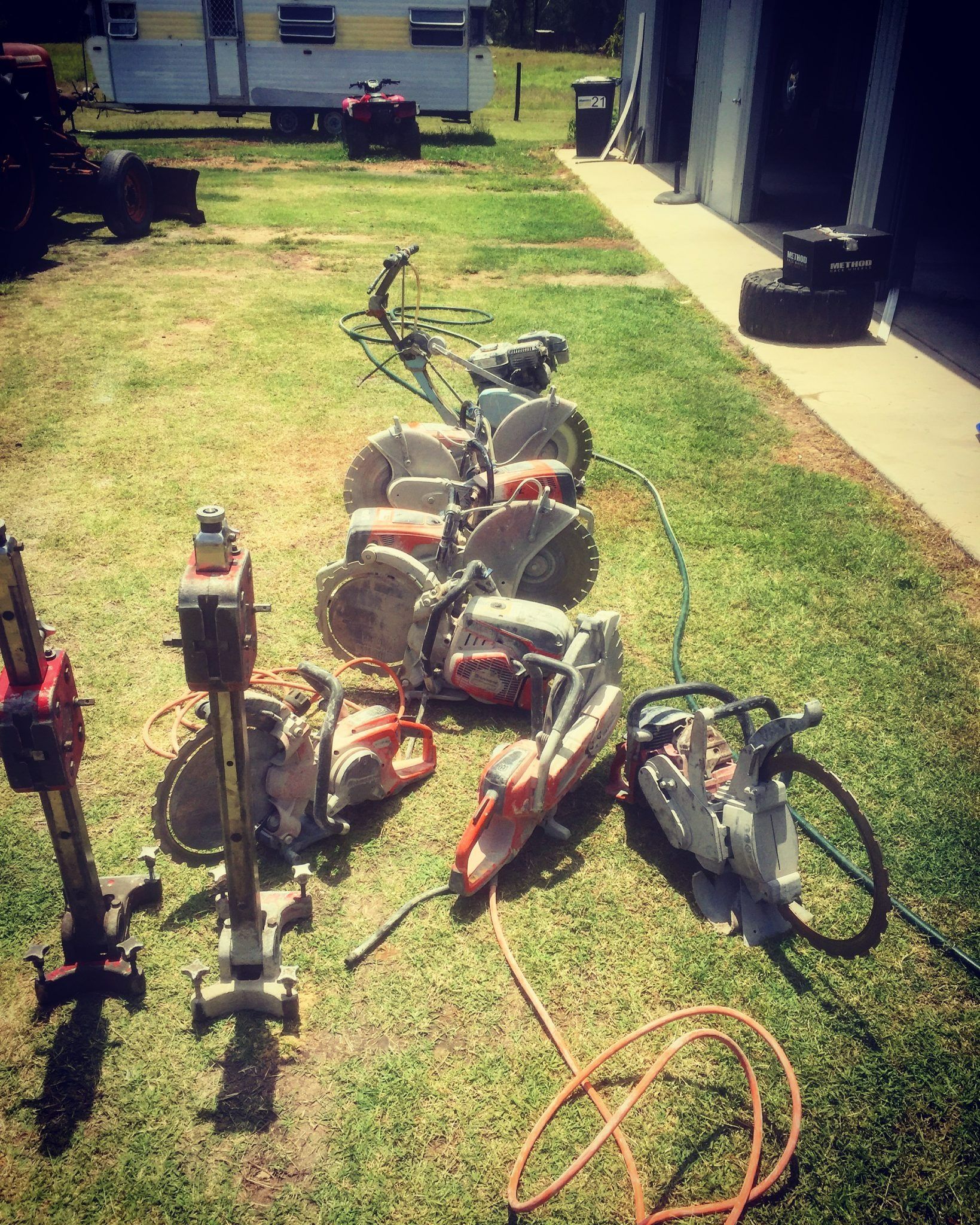 Several Concrete Saws and Cutting Equipment Laid Out on Grass — Dondarra Concrete Cutting & Drilling in Parkhurst, QLD
