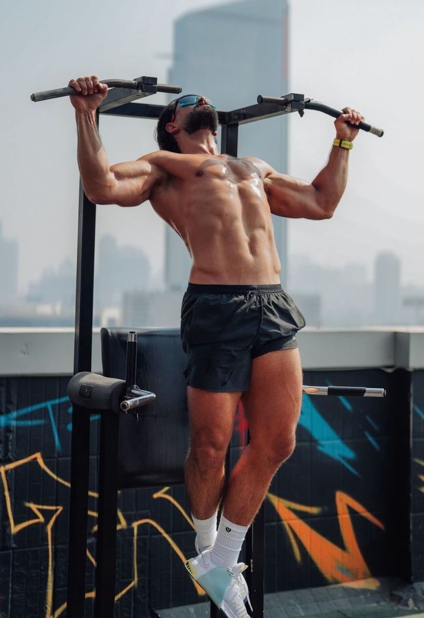 A shirtless man is doing pull ups on a machine.