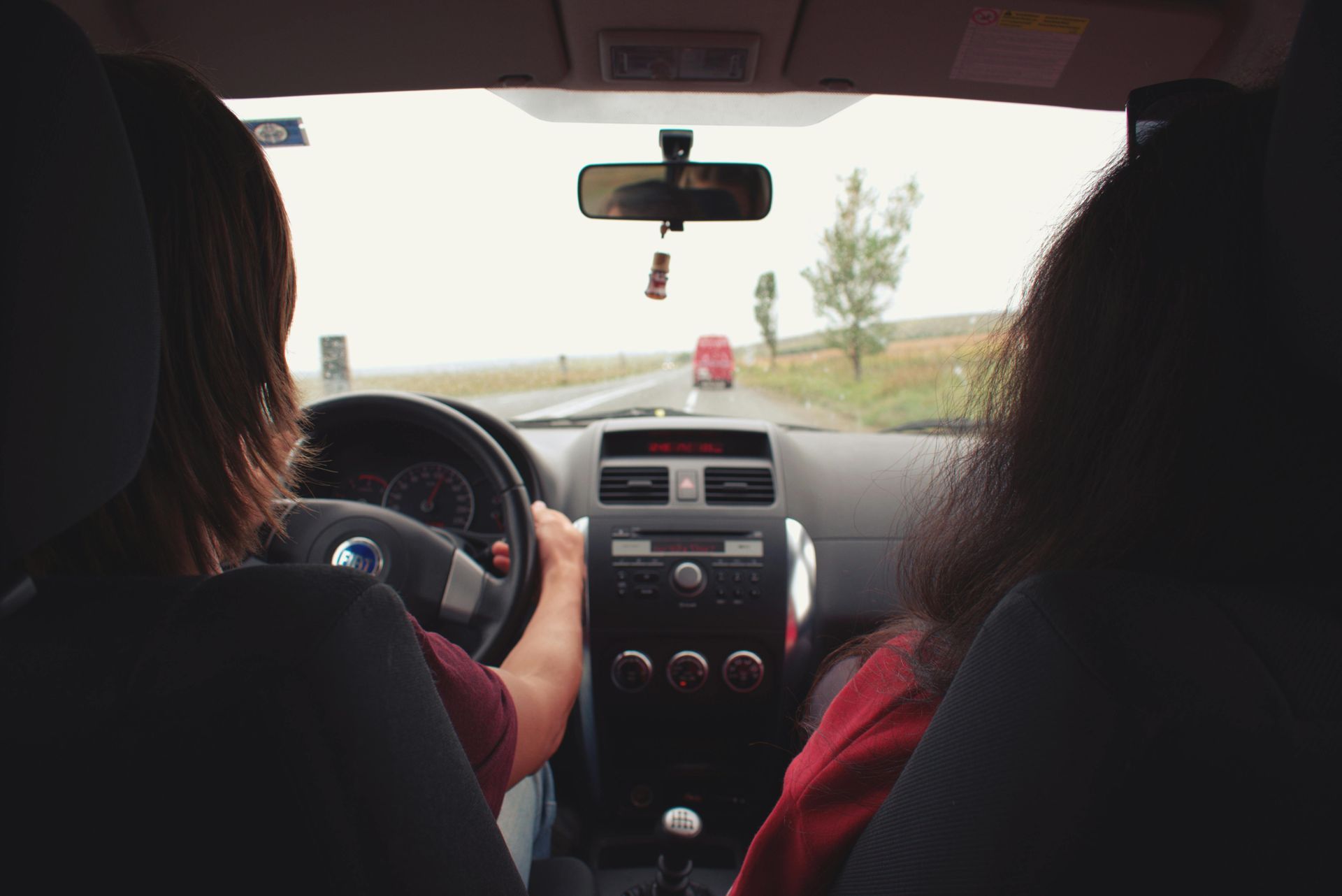 Two women are driving a car on a highway.