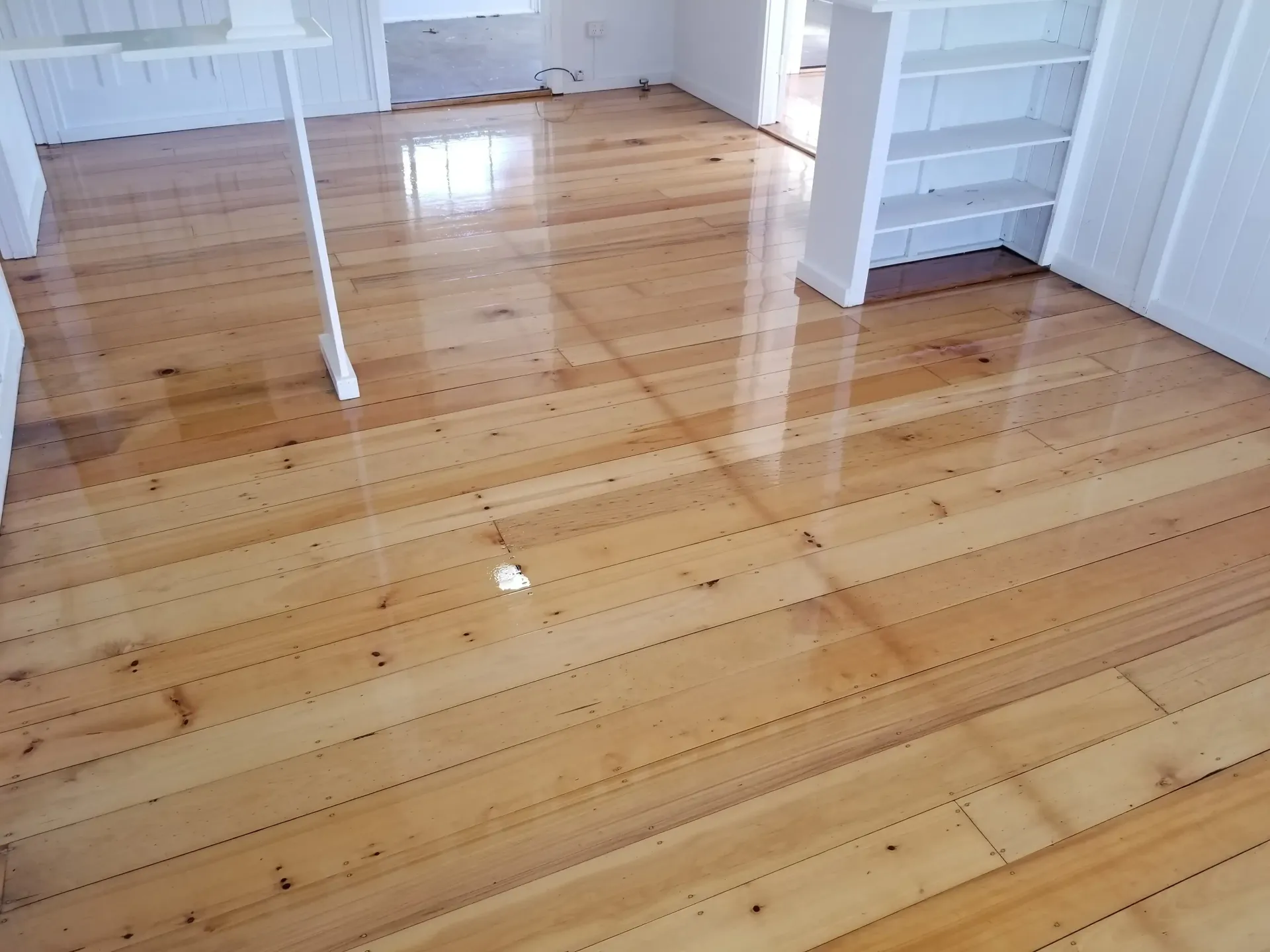 Room With Glossy Wooden Floor, White Trim, and Built-in Shelves — The Good Wood Polished Timber Floors in Highfields, QLD