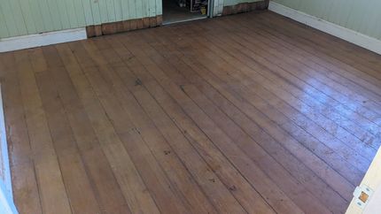 Empty Room With Worn Wooden Floor and Light Green Paneled Walls — The Good Wood Polished Timber Floors in Highfields, QLD