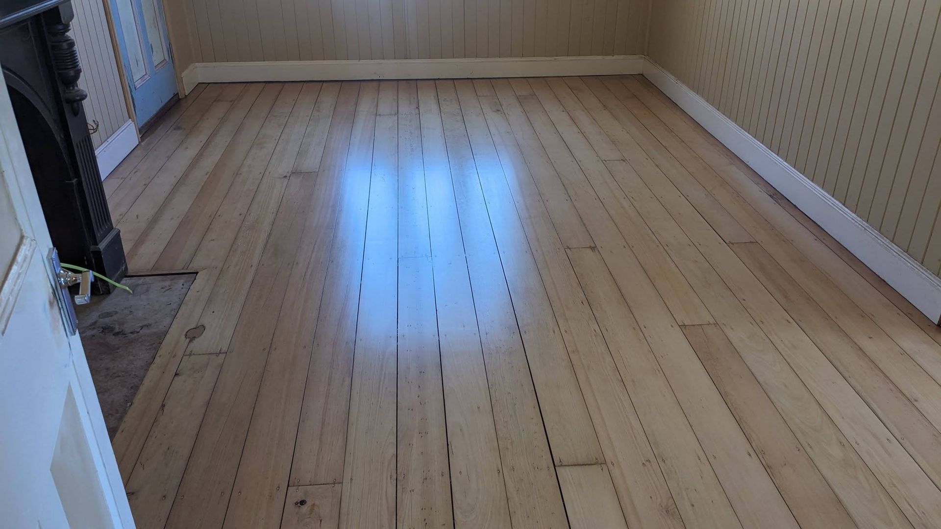 Wooden floor in a room with light-colored walls and white trim, slightly reflective surface. — The Good Wood Polished Timber Floors in Oakey, QLD