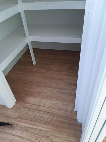 An empty white-shelved pantry with wood-look flooring. — The Good Wood Polished Timber Floors in Highfields, QLD