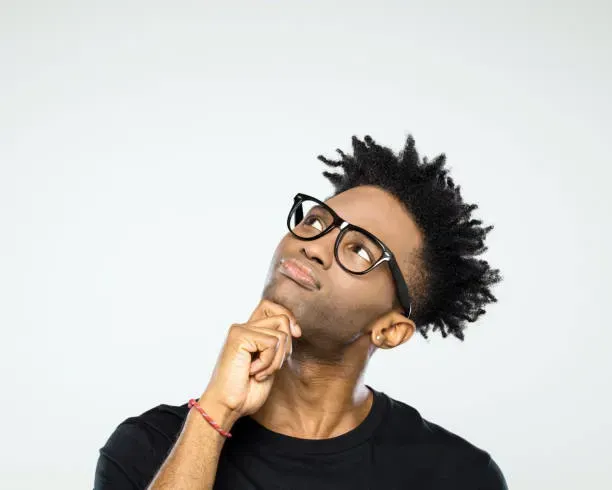 A man wearing glasses and a black shirt is looking up.
