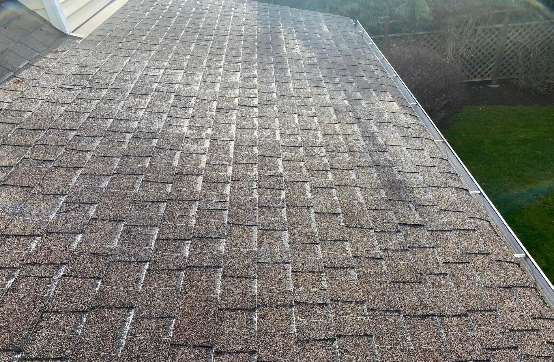 Weathered shingle roof with moss and sun glare, viewed from above