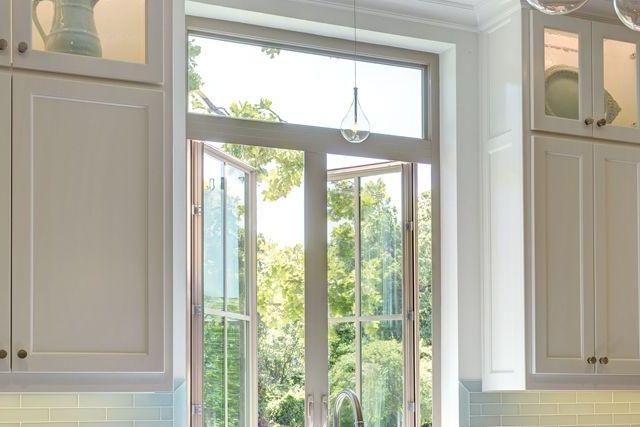 Bright kitchen window with white cabinets and a view of greenery outside