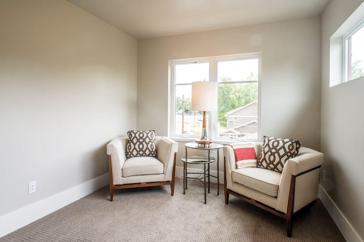 Bright living room seating area with two armchairs, side tables, and a window lamp.