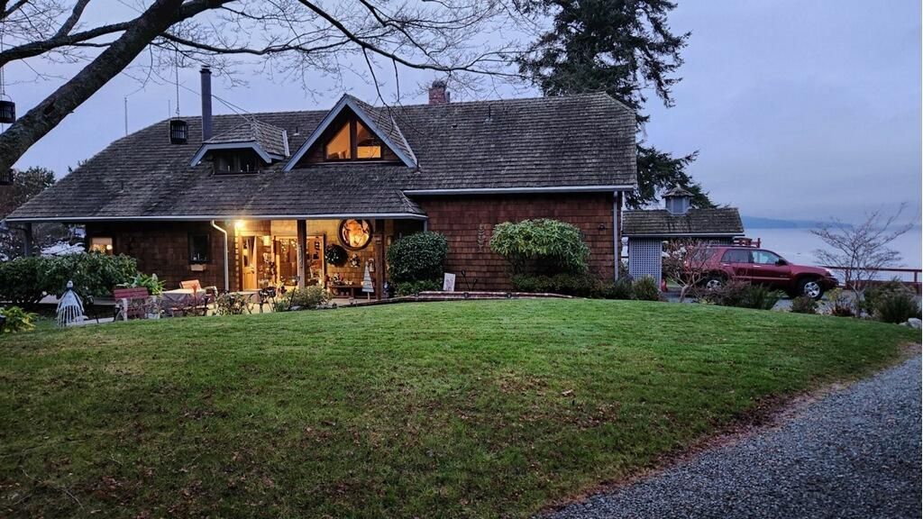 Cozy brick house glowing at dusk, with warm porch lights and a large grassy yard