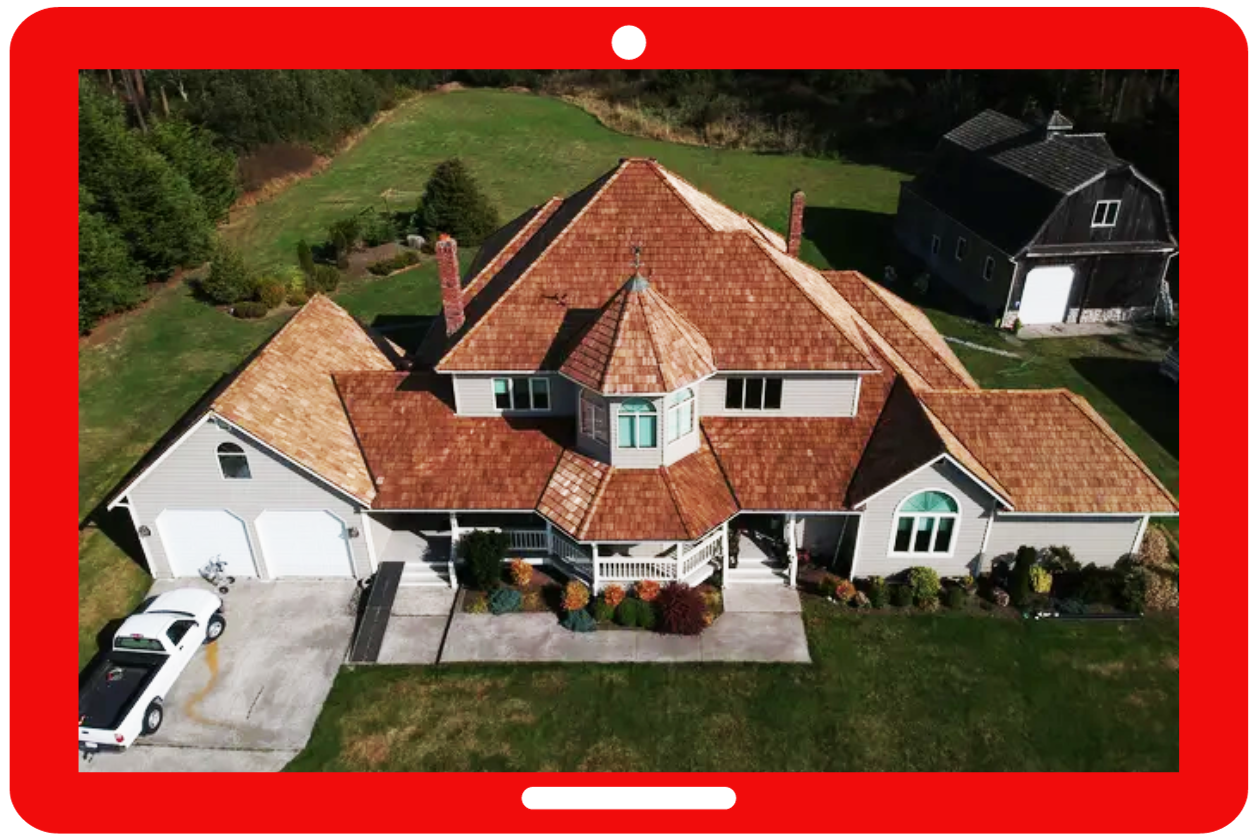Aerial view of a red-roofed house with a white driveway and green lawn, framed by a red tablet border