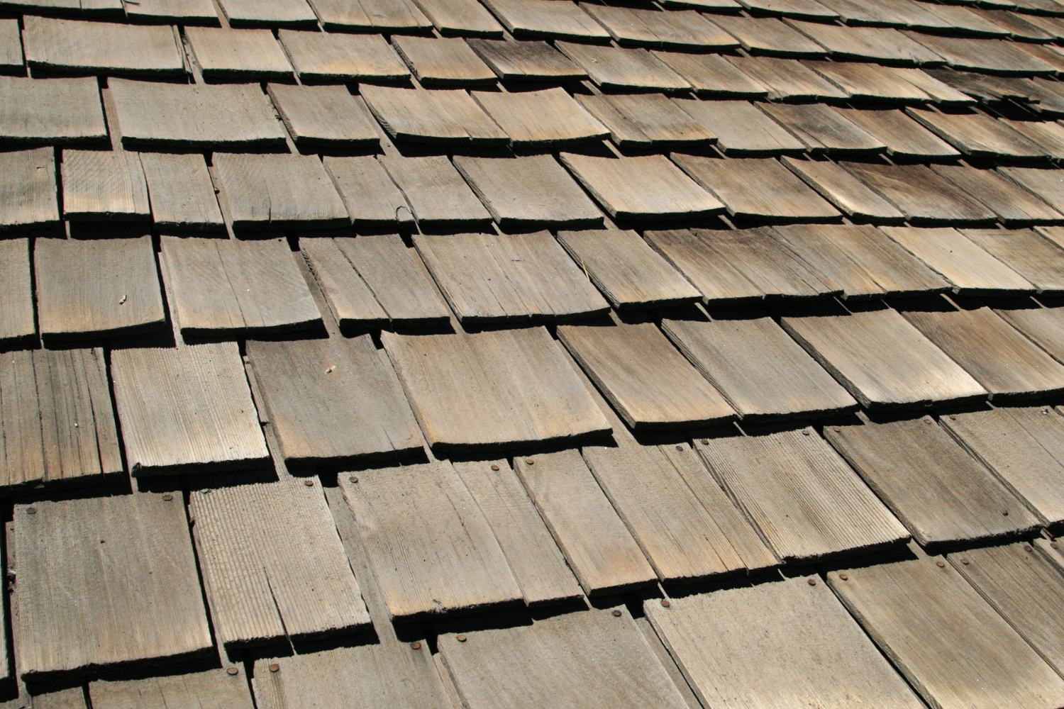 Wooden shingle roof with rows of weathered gray-brown tiles